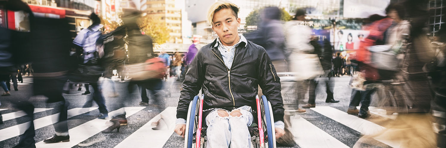 photo of a young man in a wheelchair in front of a busy crosswalk
